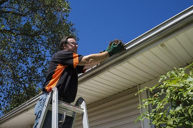 gutter repairman inspecting a damaged downspout in Arcadia Lakes, SC